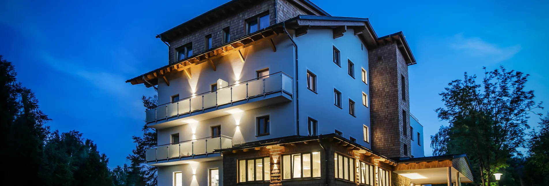 Außenansicht des R&R Residenzen Hotels in Mitterbach bei Nacht mit beleuchteter Fassade und beleuchtetem Eingangsbereich