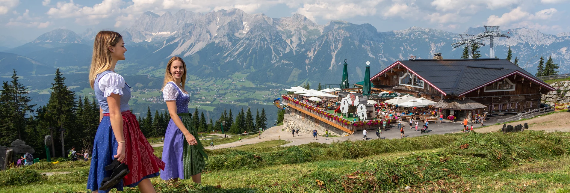 Zwei Frauen im Dirndl vor der Schaf-Alm und Bergkulisse | © Harald Steiner