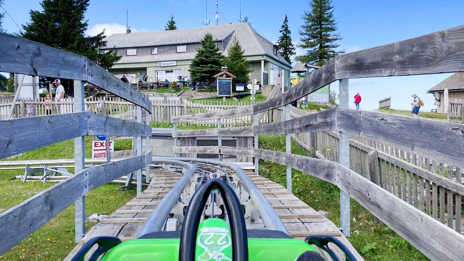 Blick auf die Sommerrodelbahn, die zu einem Gebäude führt. | © achtzigzehn - Hinterleitner