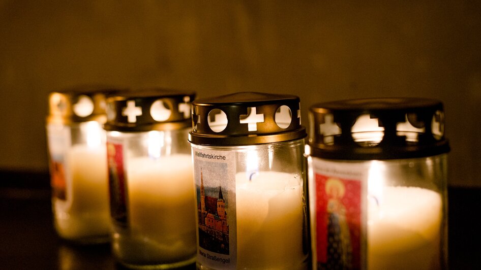 Fünf brennende Kerzen mit Etiketten in der Wallfahrtskirche.